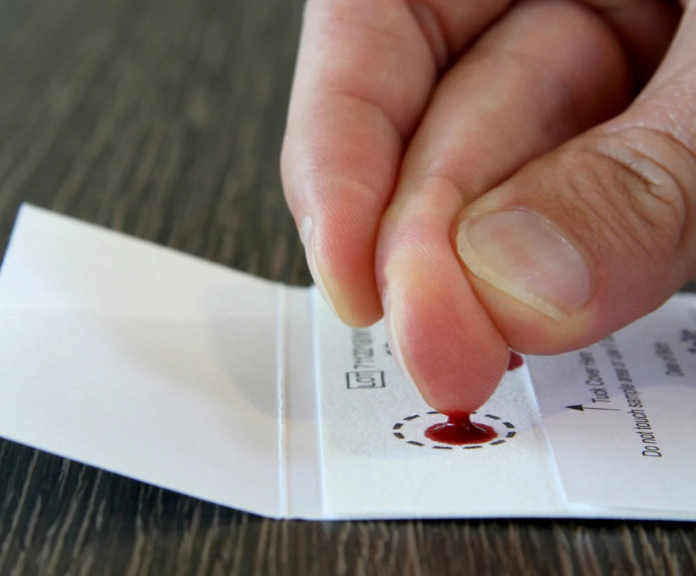 Blutstropfen für den Omega-3 Test zu Hause auf die Testkarte auftragen